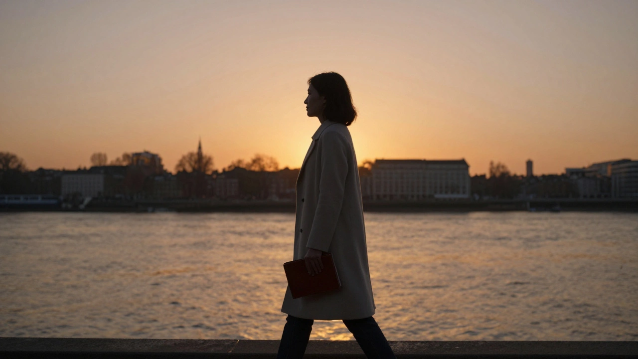 A woman walking peacefully along the Thames at sunset, silhouette against glowing sky.