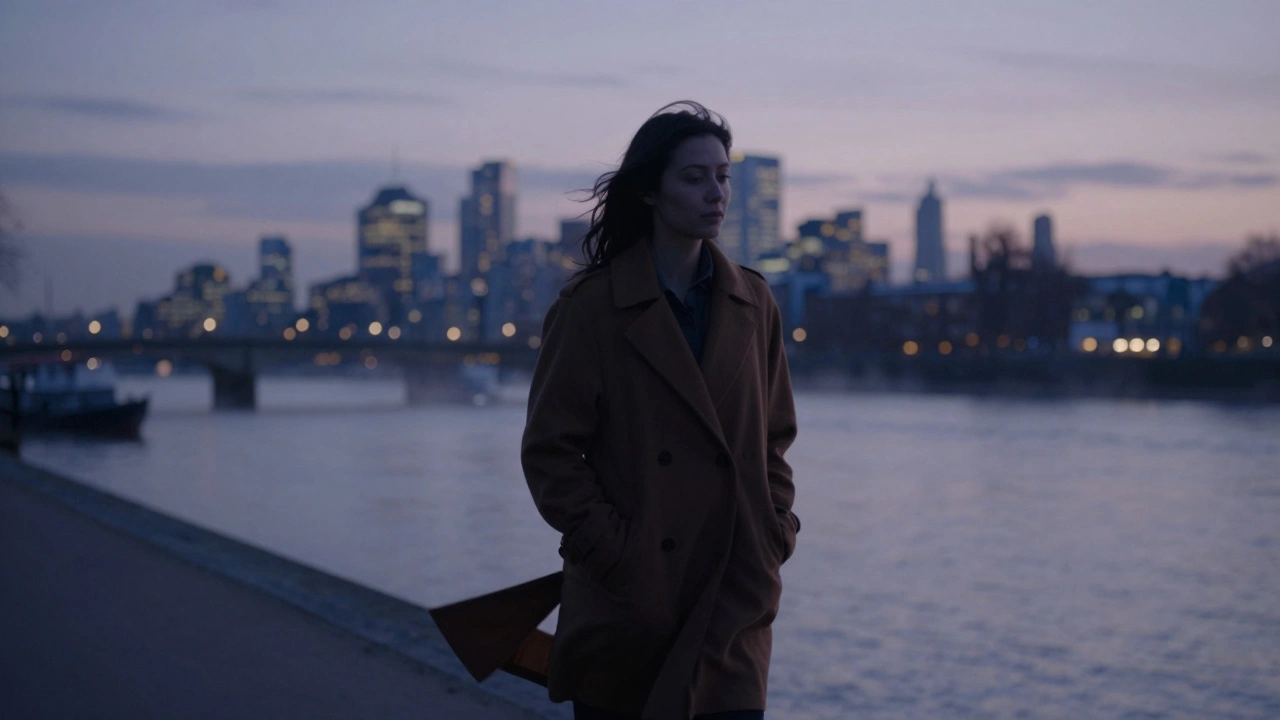 Person walking peacefully along the Thames near Isleworth at dusk, city skyline in background.