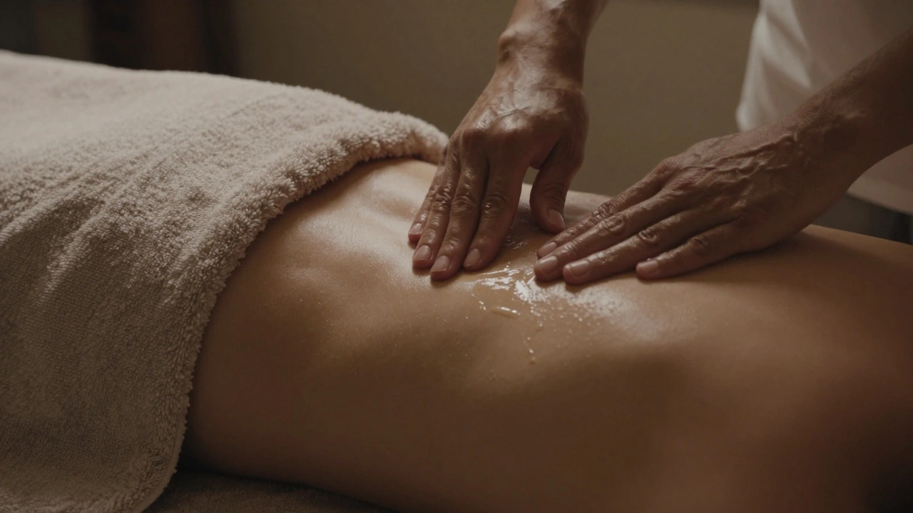 Gentle hands applying oil to a back covered by a towel, in a dim, serene space with warm lighting.